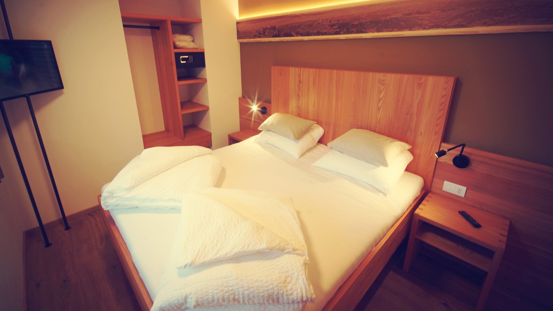 Doppelzimmer mit hochwertigem Bett und Fernseher im Chalet Frieda in Südtirol